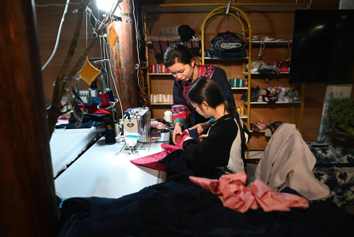 李利（后）在贵州省兴义市万峰林景区门店内与员工一起制作民族服饰（2024年2月19日摄）。新华社记者 刘续 摄