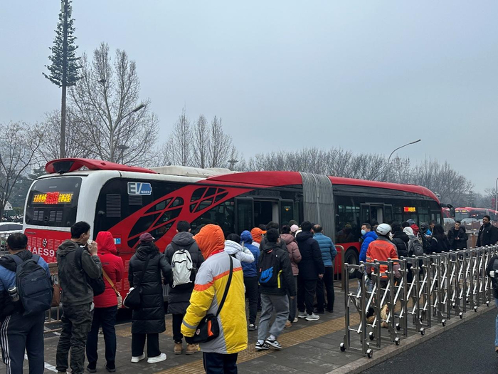 玉泉路口西公交站（向西方向），早高峰乘客排队候车，现场多名工作人员维持秩序、引导乘车。千龙网记者 徐锟 摄