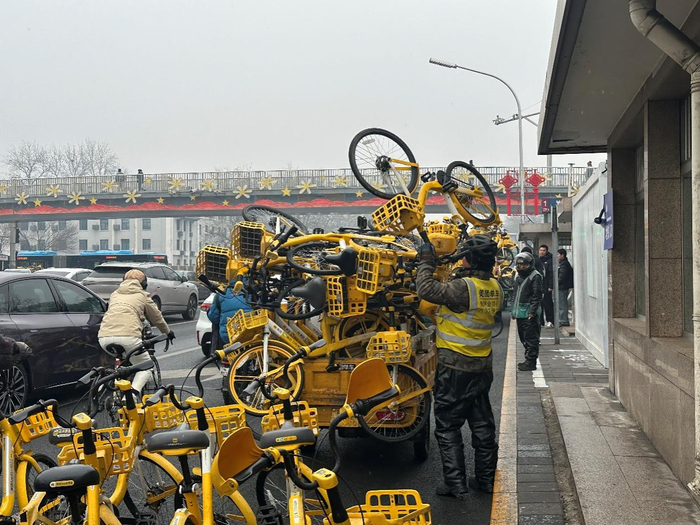 今晨7点，玉泉路地铁站外，工作人员搬运共享单车装入调度车，进行车辆调运。千龙网记者 徐锟 摄