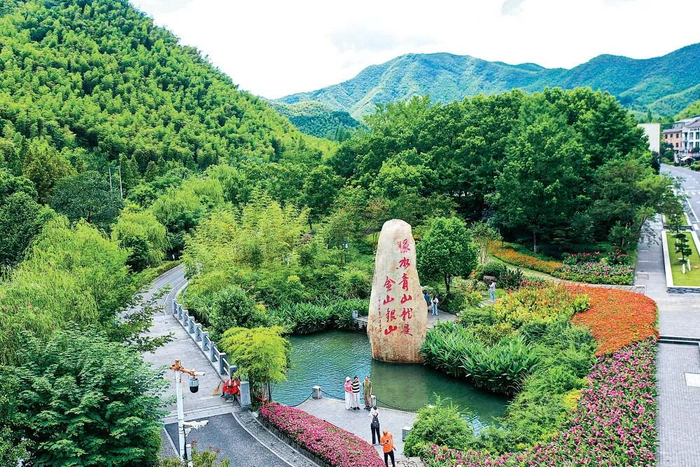 在浙江省安吉县余村，游客在刻有“绿水青山就是金山银山”的石碑前留影。图源：新华社