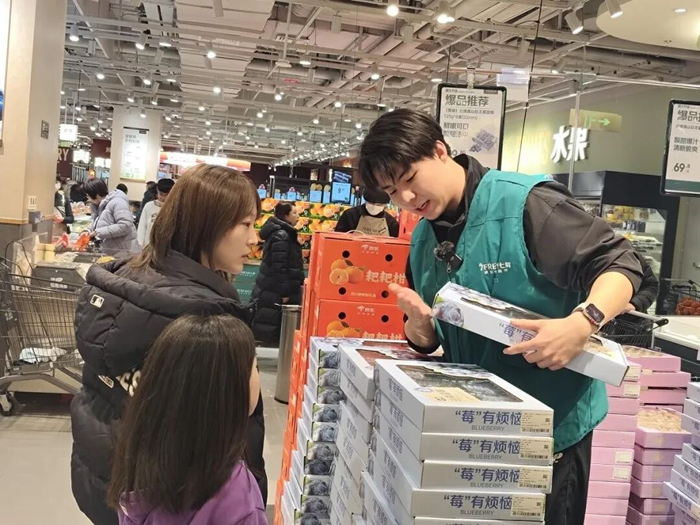 京东七鲜超市工作人员曹正向顾客详细介绍蓝莓品质。赵宗祥 摄