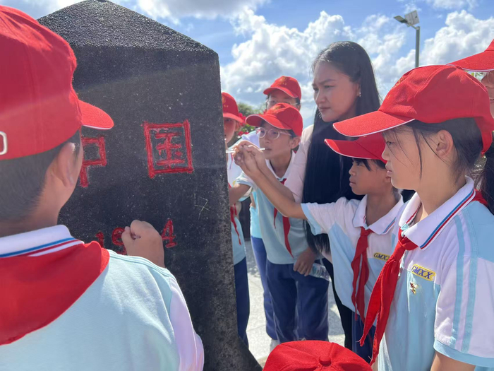 李瑞芳带领孩子们为界碑描红
