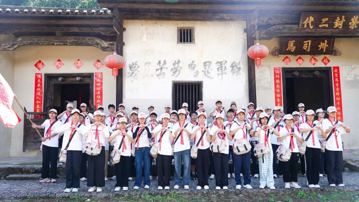 ▲“我的井冈行”研学人员在井冈山行洲村红军标语前集体“比心”。