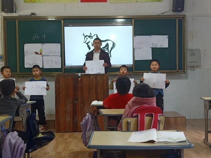 　　▲李先明老师在课堂上教孩子们画牛