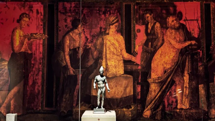 青铜小雕像陈列在复制的庞贝室内壁画前。本文摄影/本刊记者 倪伟