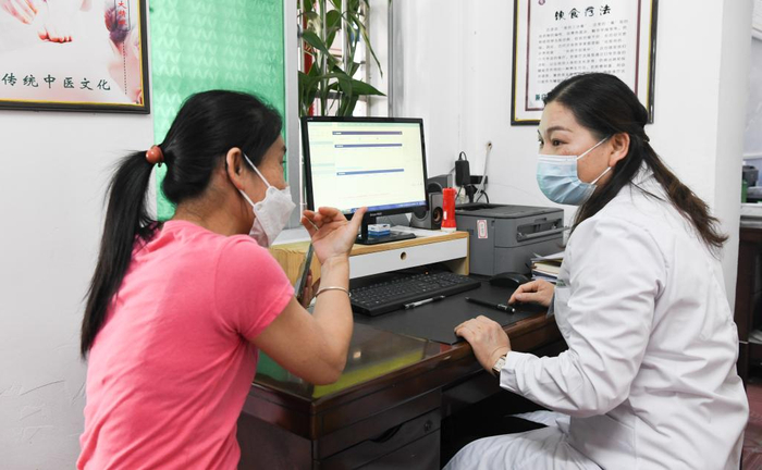 在海南省白沙黎族自治县七坊镇社区医院，韦小丽（右）在为病人看诊（图片摄于2023年2月13日）。新华社记者 杨冠宇 摄