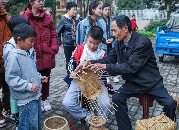 在长兴县泗安镇罗家地村的文化广场，竹编艺人指导放秋假的学生们学习竹编技艺。新华社记者 徐昱 摄