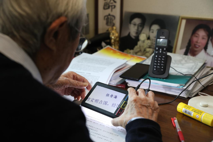 2025年3月，张晋藩先生在公开课上课前用放大镜备课。新华社发