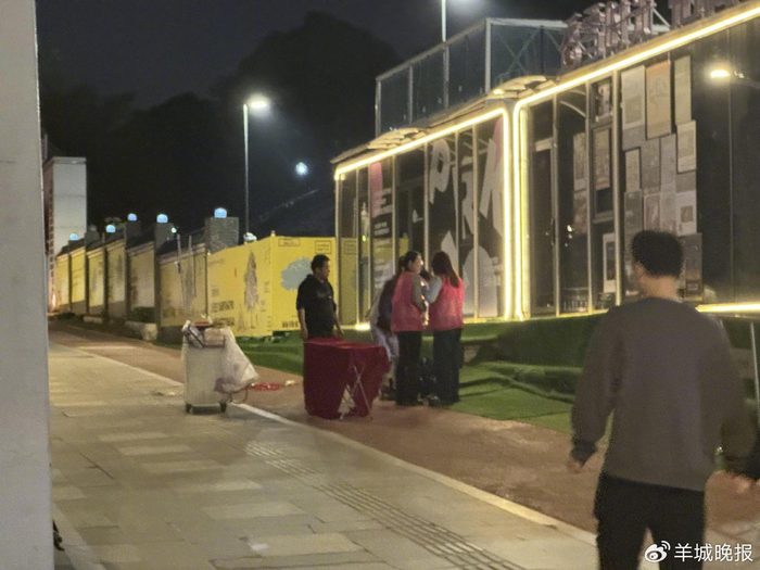 演唱会散场时，在主通道旁，有两名身穿红色马甲的女生在兜售专辑与海报​