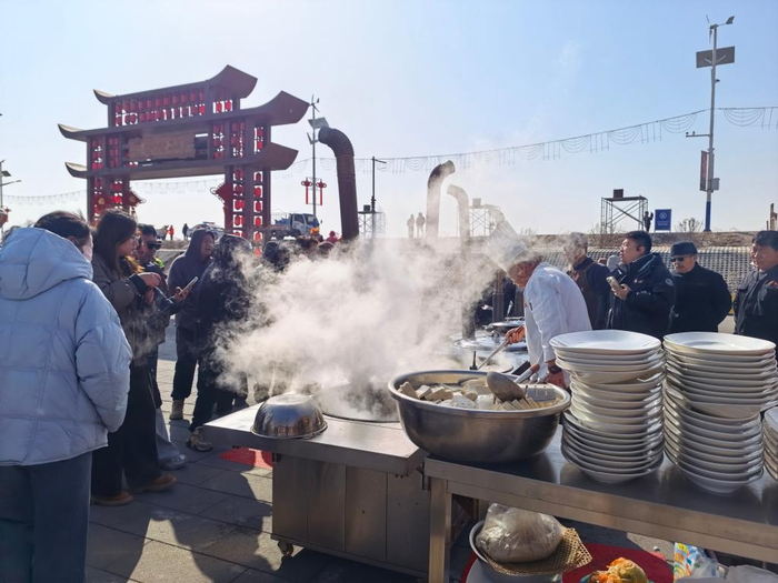 　　内蒙古包头市画匠营子村黄河岸堤旁游客围看厨师炖鱼。新华社记者 贺书琛 摄