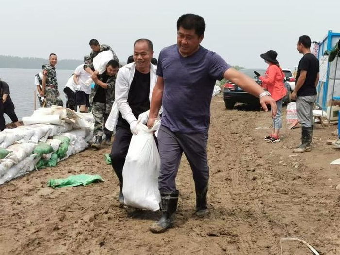 2020年汛期，吴劲松和村民提沙包加固大堤。新华社发（外岭村供图）
