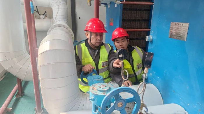 热力公司工作人员在新改建的小区换热站维护设施。