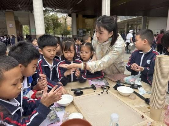 图为:唐小玲通过非遗进校园推广冷凝香文化 教会学生识别化工合香珠