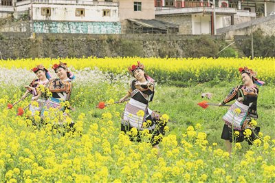 游客身着民族服饰在乌当区新堡布依族乡王岗村油菜花田里跳舞。     黎荣 摄