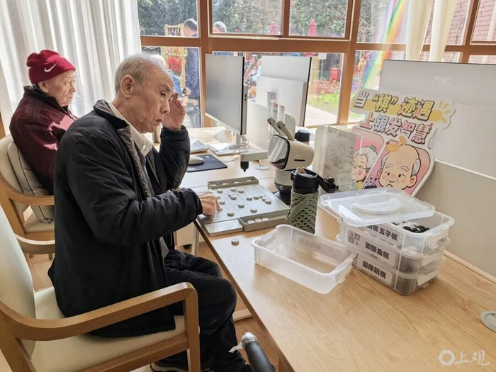 老人正在和机器人下棋、看视频。周楠 摄