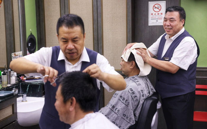 3月20日，四联美发王府井店，理发师一边剪头一边和客人聊天。新京报记者 李木易 摄
