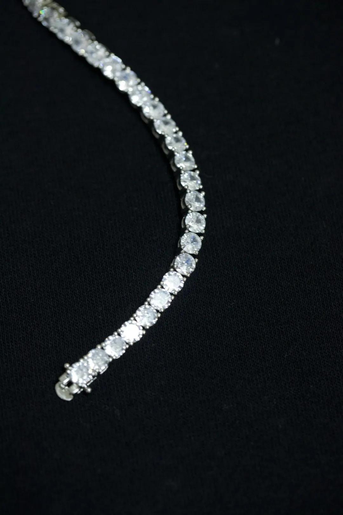 采用单排密钉镶工艺，方形镶口将每一颗宝石整齐排列，宝石之间间距极小，托底扁平贴手，视觉重心完全聚焦于锆石的锋利切面，呈现出干净利落的几何美感。