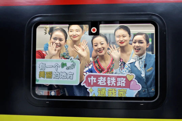 中老铁路通车首日，乘务员举牌庆祝。陈飞 摄