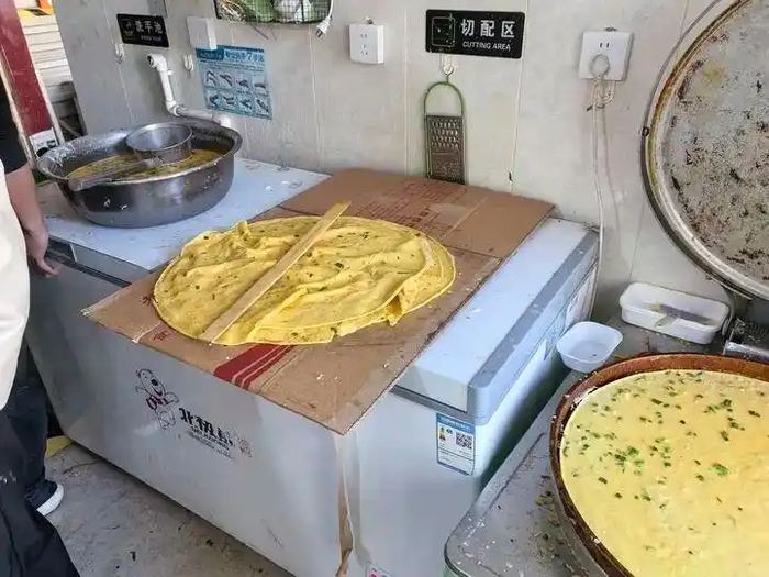 图为某外卖门店后厨的场景，煎饼直接放置在纸壳上。