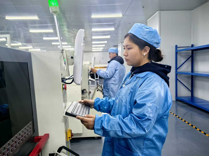 工人在生产线上操作设备。代玲摄