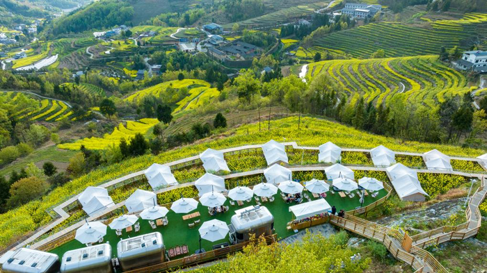 　　游客在凤堰梯田一处营地欣赏油菜花海。新华社发（邵向东摄）