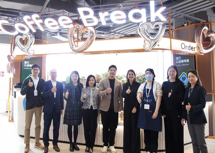 图为谭陆洁（右四）与同事在渣打中国公益咖啡角与项目受益者“无碍理想”酒馆创始人及“星拉茶”调饮师合影交流（受访者供图）