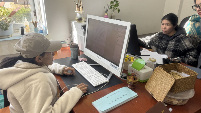 图为尼珍（左一）在进行资产登记工作。