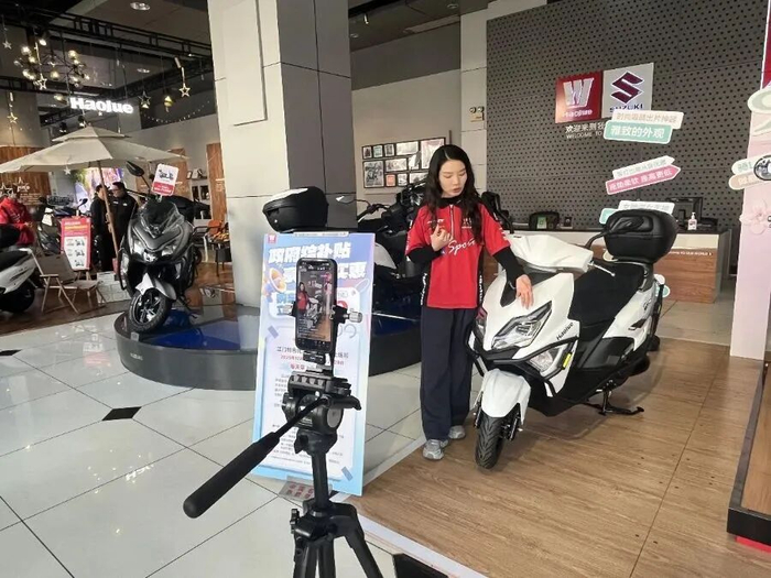 图为江门一摩托车线下店，主播正在推介车型，吸引众多车友在线咨询下单