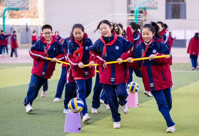 学生在操场参加三人绕桩跑趣味游戏。中国教育报-中国教育新闻网通讯员 丁根厚 摄