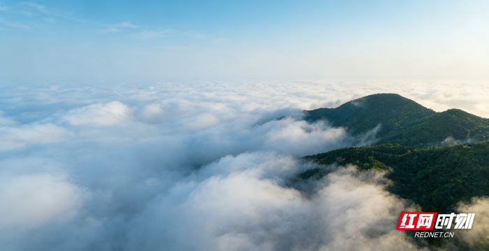 云海翻涌，山峰在一侧静静伫立，好似在守护这片仙境。（文峰 摄）