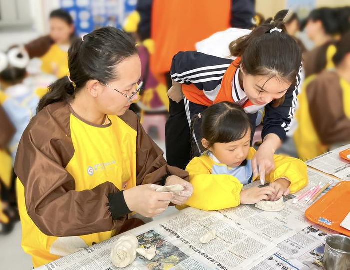 在古城幼儿园，孩子们用画笔描绘城墙，用黏土制作古建模型。