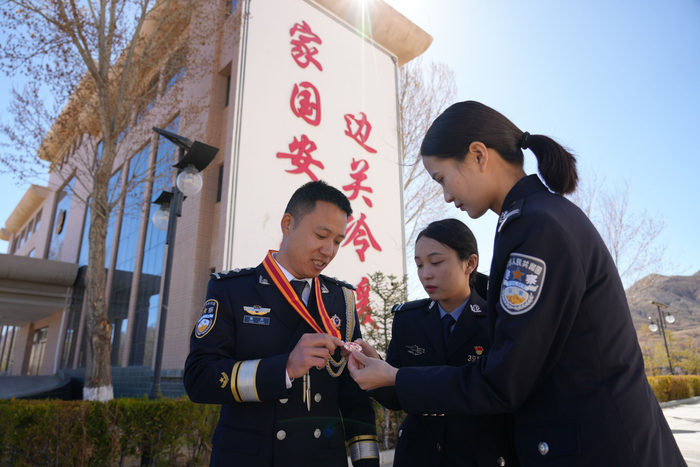 图为获得纪念章的戍边民警在跟战友分享自己的纪念章。