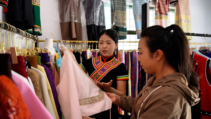 黄显翠正在为游客介绍少数民族服装。宋菲菲摄