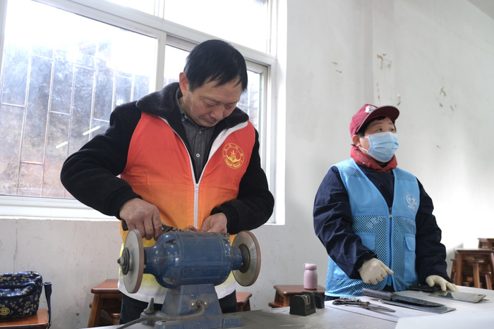 趁着维修家电的间隙，阿强师傅主动帮居民磨菜刀。甬派资料图