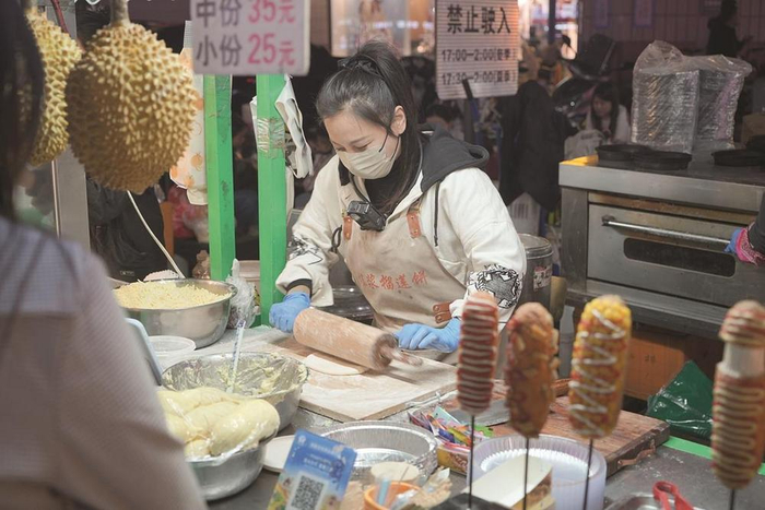         新华街夜市摊主边直播边卖货。  张琪 摄    