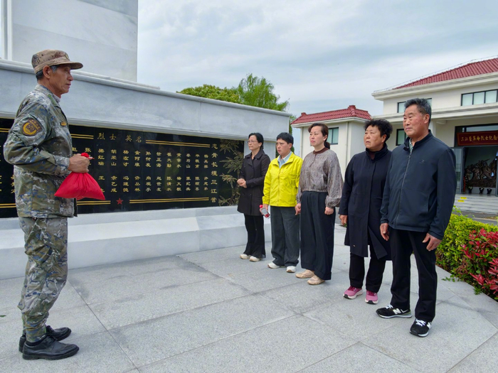 三江营革命烈士纪念馆守陵人张明海（左一）向烈士亲人敬送“三江土”