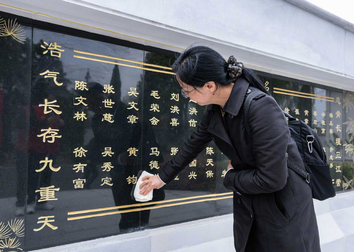 黄钧烈士的孙女黄熊熊擦拭墓碑上爷爷的名字