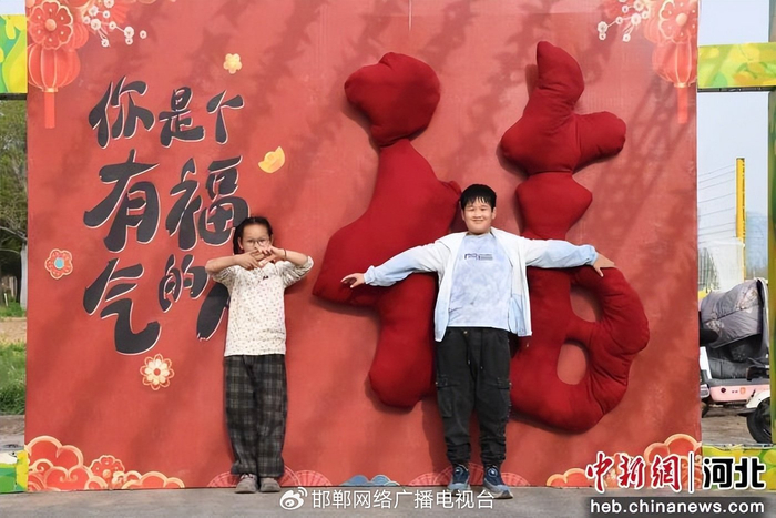 图为游客在油菜花景区内打卡墙前拍照。 许朋钰 摄