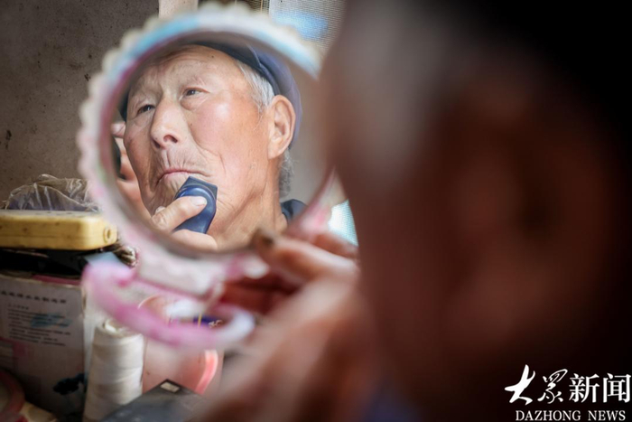 听到了村书记的广播，80岁的村民国洪民刮刮胡子，换身衣服，想要拍个精神的照片。