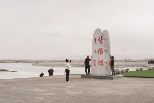 游客在情侣湖边拍照打卡。