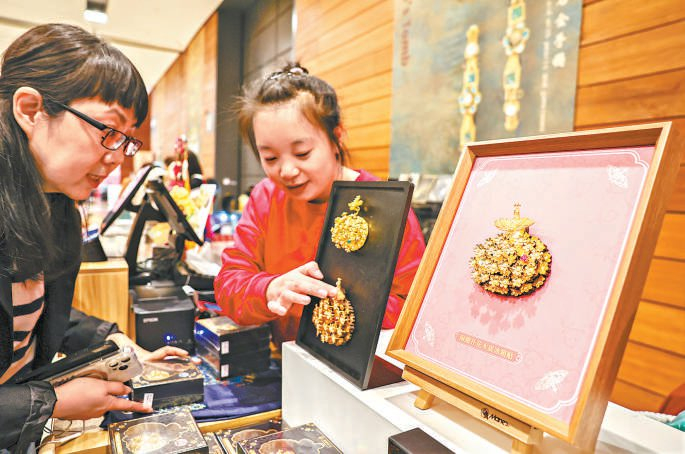 　　销售人员正在介绍闹蛾扑花冰箱贴。 本报记者 邓伟摄