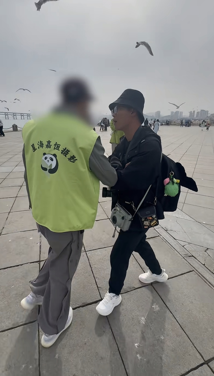 身穿“星海嘉恒摄影”工作服的人员驱赶个人摄影师。（视频截图）