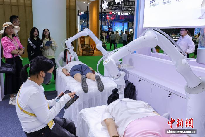4月13日，第六届中国国际消费品博览会在海南海口举办，图为参观者在现场体验一款按摩机器人。　中新社记者 骆云飞 摄 