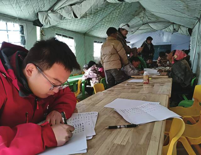 在震区 安置 点“青青儿童乐园”，张云飞为小朋友们批改作业