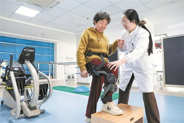     4月7日，在江苏省海安市中医院康复训练中心，一名患者在治疗师的指导下穿戴外骨骼机器人进行康复训练。    新华社发（顾彬斌  摄）