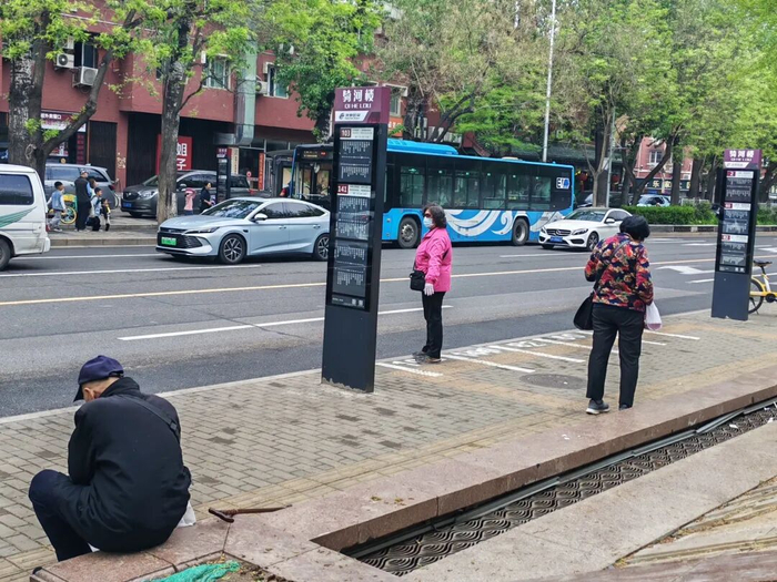 骑河楼站，一名大爷坐在路边候车。