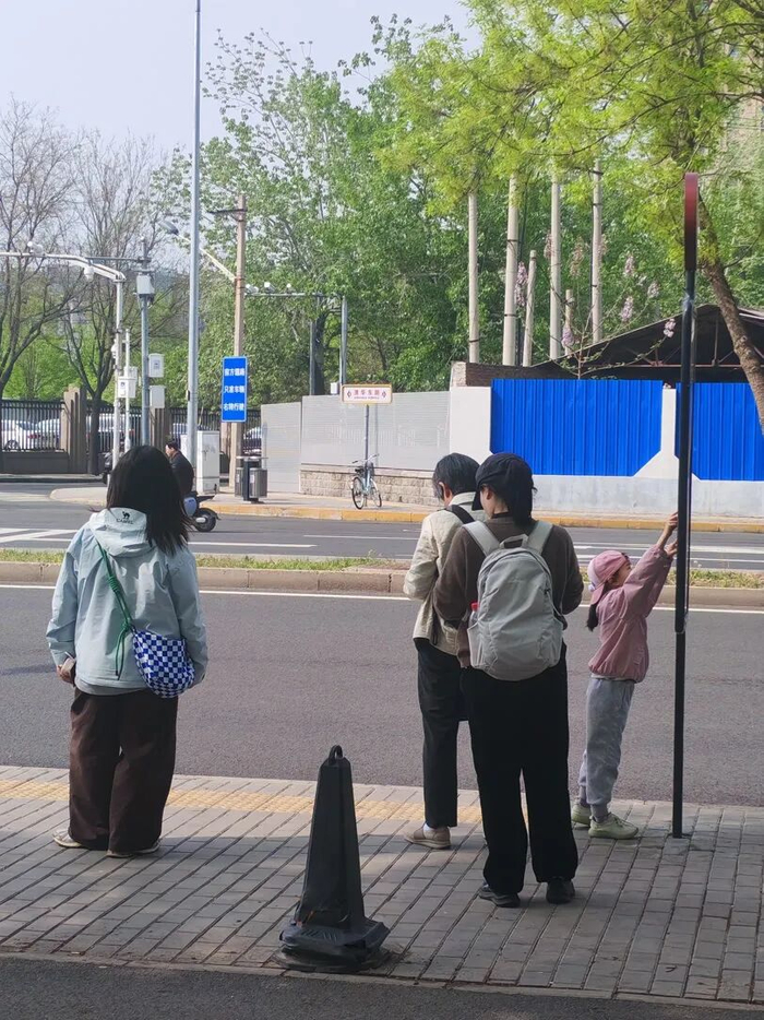 清华东路西口站，在树荫下候车的市民。