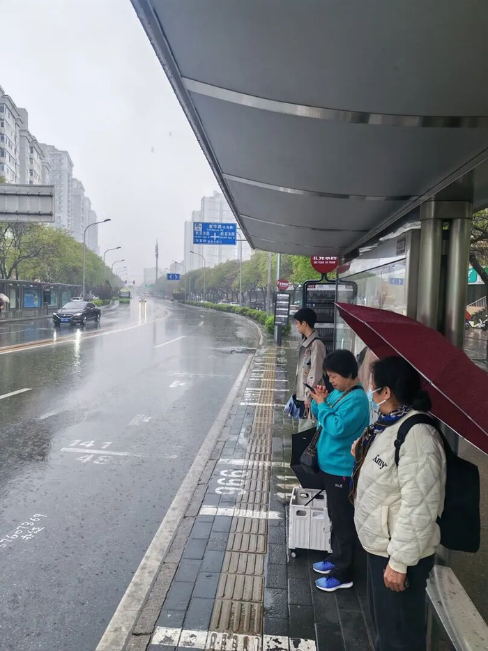 北苑家园站，市民躲在有雨篷的一侧候车。