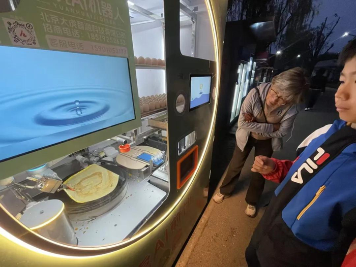 朝阳公园内的AI煎饼机器人，正在被人围观。