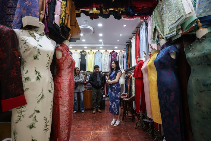 一位准备返回英国伦敦参加毕业典礼的留学生正在博旺服饰定制店内试穿旗袍。